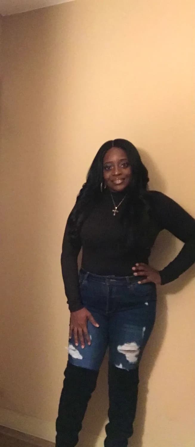 Smiling woman in black top and distressed jeans