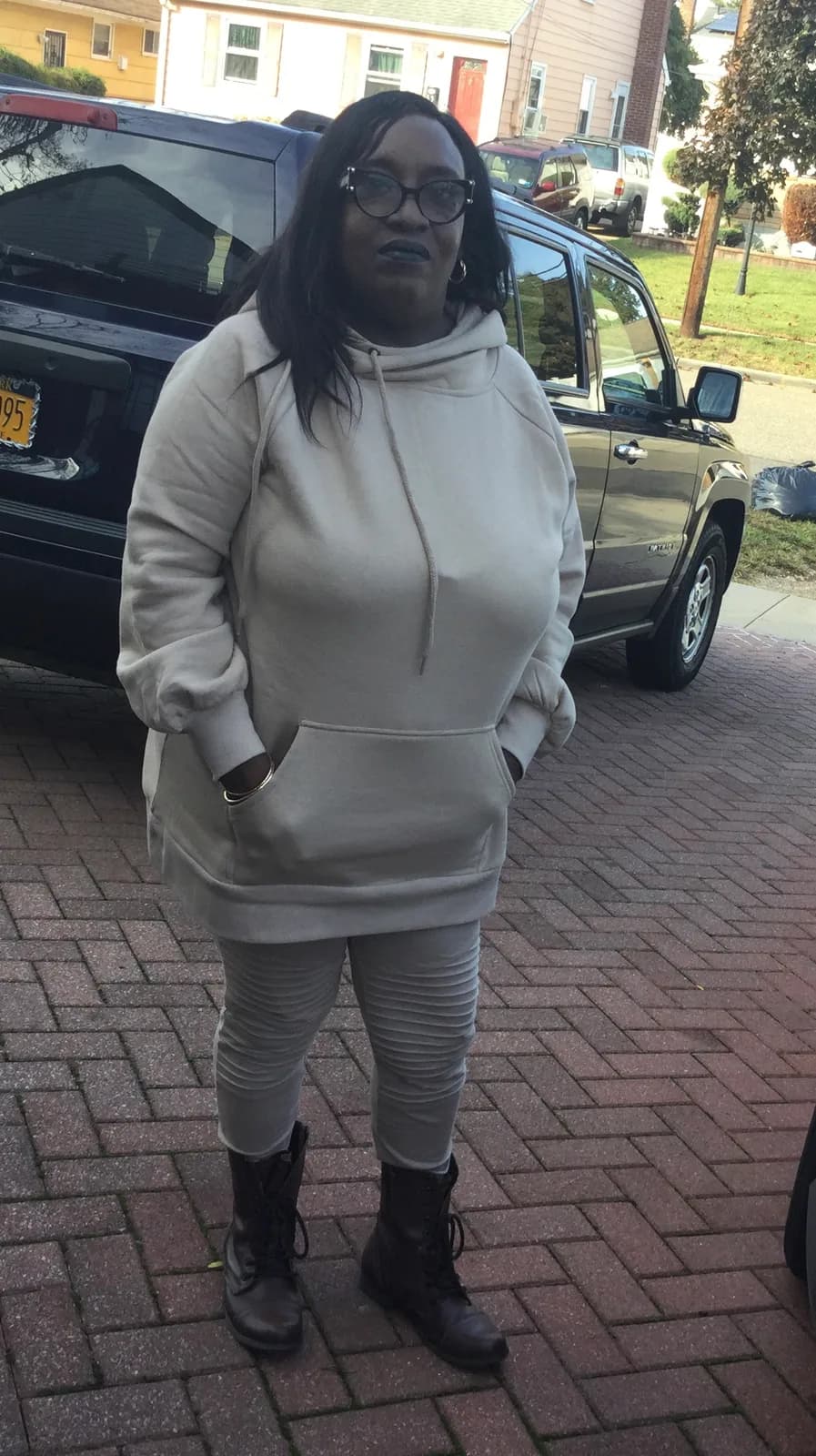 Woman in light hoodie and leggings on brick driveway